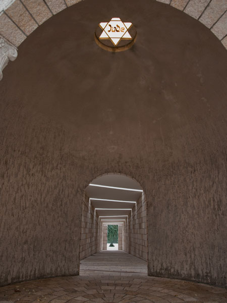 Jude Star: Piercing the dark interior of the dome is a shaft of yellow light projected from a central yellow Star of David with the black letters Jude, reminiscent of the patches Jews were made to wear during Hitler's reign.